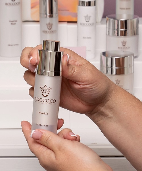 Woman holding Roccoco Botanicals Vitaskin bottle